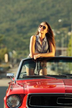 Beautiful young woman in a convertible car enjoying a summer day