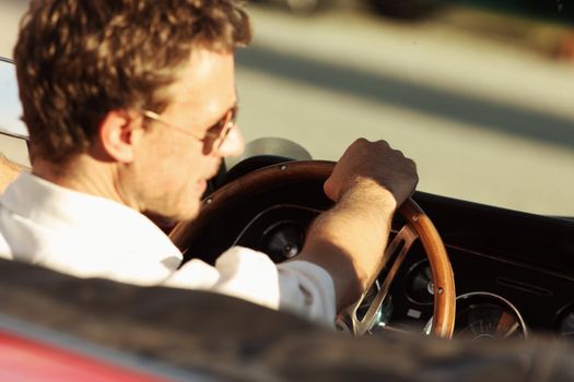 Handsome man driving a convertible car, focus on hand
