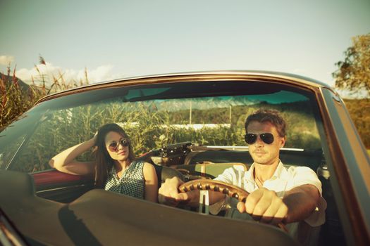 Couple taking a road trip in vintage convertible