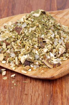 Heap of Spicy Mix with White Pepper, Thyme Seeds, Chopped Dried Mushrooms and Scented Herbs in Wooden Spoon closeup on Wooden background