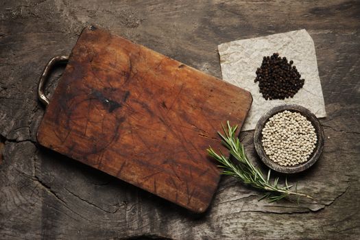 Cutting Board, rosemary and spices on a old wooden table