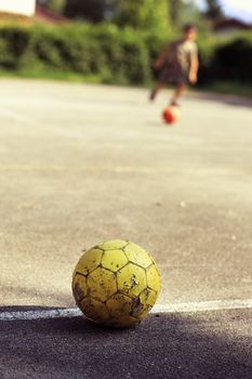 Old yellow soccer ball, young boy playing on background