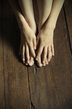 Hands and feet of woman on a wooden floor