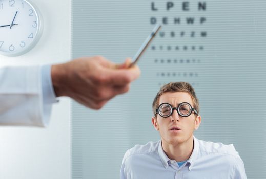Optometrist pointing at eye chart, a nerd patient having difficulty