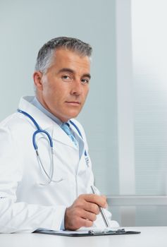 Mature male doctor sitting at desk in doctor's room