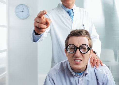 Optometrist pointing at eye chart, a nerd patient having difficulty