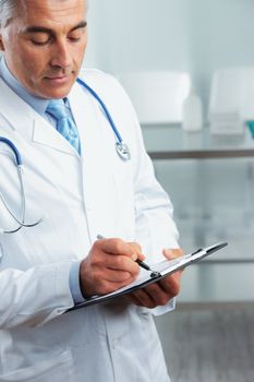  Portrait of a handsome doctor writing on clipboard 