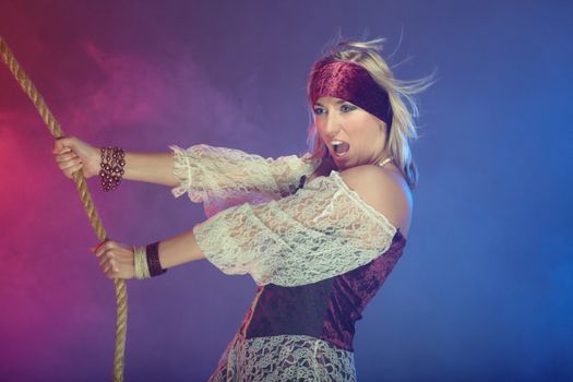 Fashionable lady in the pirate costume holding the rope in the heavy smoke