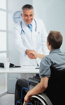 Mature doctor congratulates his disabled patient on a successful treatment