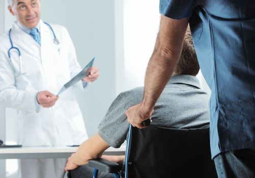 Male nurse pushing her patient on a wheelchair to meeting orthopedic doctor