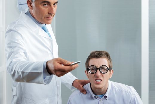 Optometrist pointing at eye chart, a nerd patient having difficulty