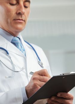 Close up shot of a male doctor writing on clipboard 
