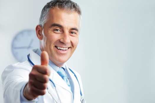 Portrait of middle-aged doctor showing you a thumbs up and smiling