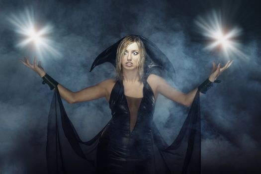 Woman in the Halloween witch costume in heavy smoke with magic flares and flashes
