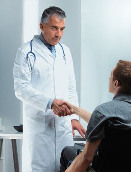 Mature doctor congratulates his disabled patient on a successful treatment