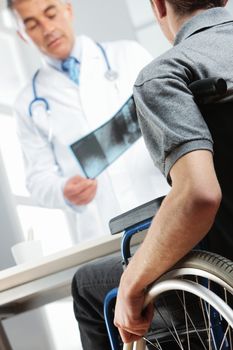 Young man on wheelchair meeting orthopedic doctor. 