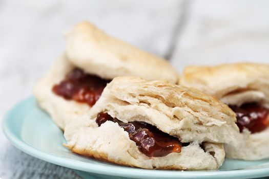 Closeup of freshly baked scones at the breakfast table with strawberry jam. Extreme shallow depth of field with selective focus.