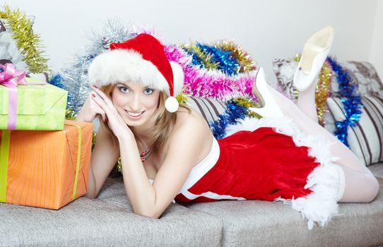 Lady in the red Santa Claus costume laying indoors near the Christmas gifts