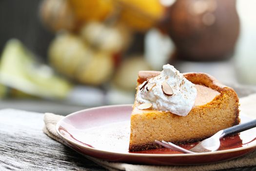 A slice of Pumpkin Cheesecake Pie with homemade whipped cream, almonds and pumpkin spice. Extreme shallow depth of field.