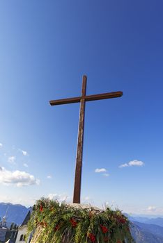 Wooden cross with blue sky, pine branches and berries - Lussari Italy