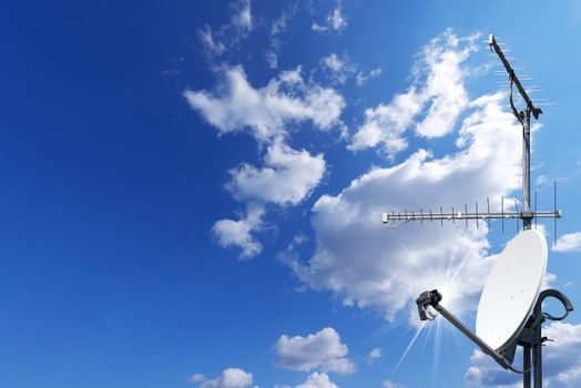 One satellite dish and two TV antennas with a beautiful blue sky