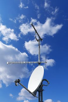 One satellite dish and two TV antennas with a beautiful blue sky