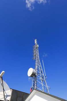 Communication tower and satellite dish on the roof with a beautiful blue sky