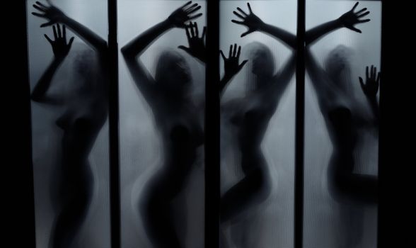 Silhouette of the naked lady dancing behind the glass