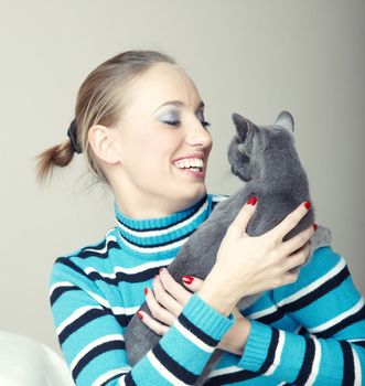 Smiling lady plays with cat indoors