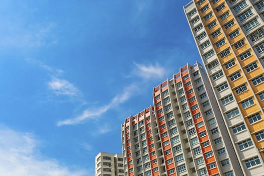 A low angle shot of a new colorful high rise apartment against the sky.