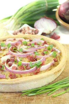 Onion tart with leeks and bacon on a light background
