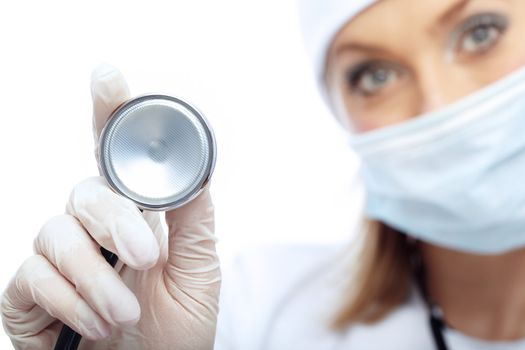 Close-up photo of the stethoscope and blurred docror in mask