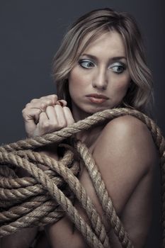 Suffering lady bonding by the rope. Studio portrait