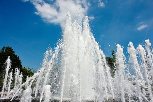 Water jet in a city park fountain with clear blue sky as background                               