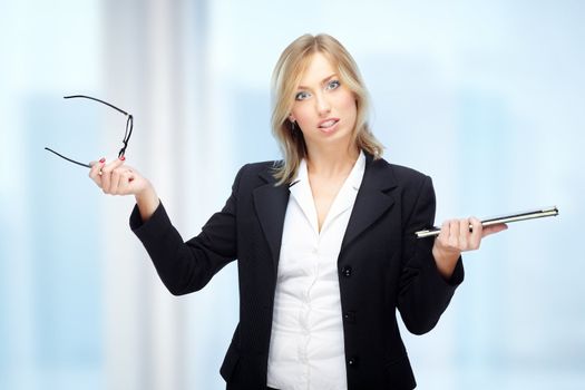 Angry businesswoman in office holding folder and eyeglasses