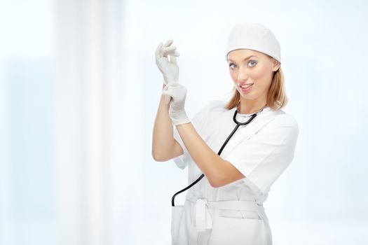 Pretty female doctor putting on the latex gloves at hospital