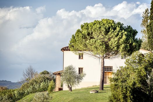 Picture of a typical house with tree and clouds on blue sky in Tuscany, Italy