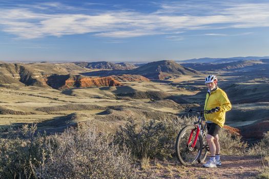 senior male mountain biking in rugged terrain with cliffs and canyon of Red Mountain Open Space in northern Colorado near Fort Collins