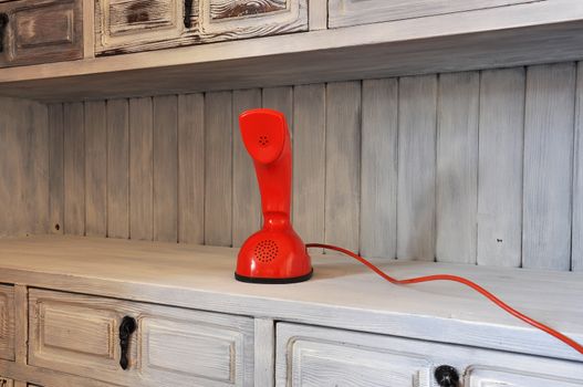 Red Cobra phone in an old fashioned cabinet.