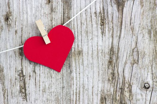 red heart hanging on line against old wood-grain wall