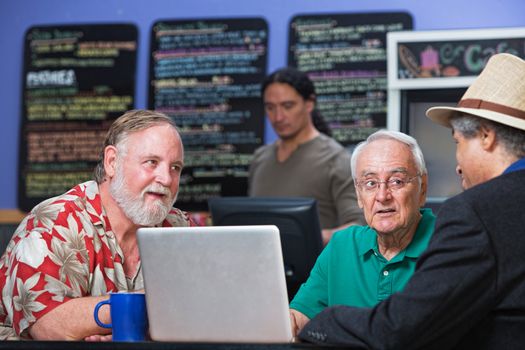 Diverse group of mature men in cafe with laptop