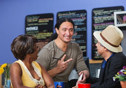 Handsome cafe owner with diverse customers taking orders