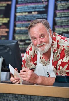 Grinning man in beard and mustache working at a cafe