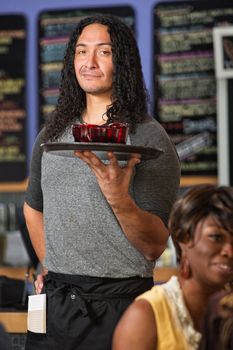 Male Hispanic cafe waiter serving drinks to customers