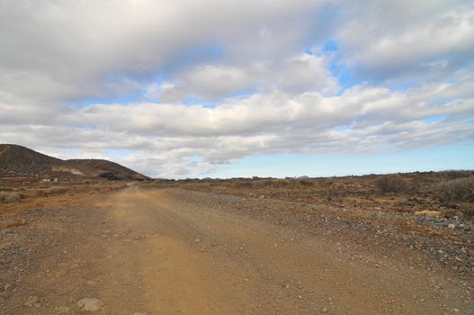 Sand and Rocks Road in the Desert on a Cloudy Sky