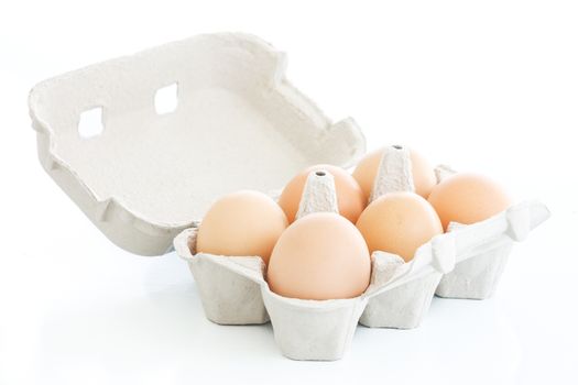 Six eggs on a carton box over a white background