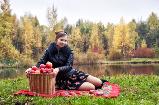 haughty woman with a basket of apples on a picnic