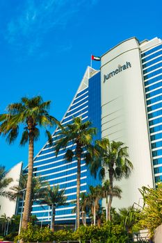 DUBAI, UAE - November 15: Palm trees waving in the wind and giant chess board in front of Jumeirah Beach Hotel, wave-shaped luxury resort, well-known Dubai landmark, on November 15, 2012, Dubai, UAE.