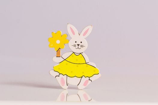 Easter bunny helding yellow flower on white background