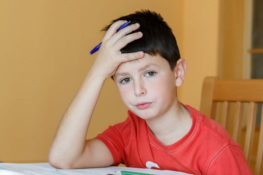 boy doing school homework, is tired and bored